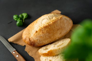 Çıtır ekmek ve mutfak bıçağı, siyah arka planda fesleğen. Dilimlenmiş beyaz ekmek. Gıda arkaplanı