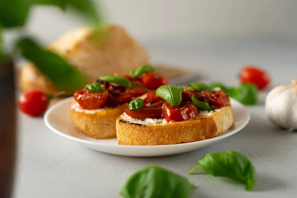 stock image Bruschetta with Ricotto cheese and cherry Tomatoes, basil, garlic on a grey concrete background. Food. Food background. Close-up