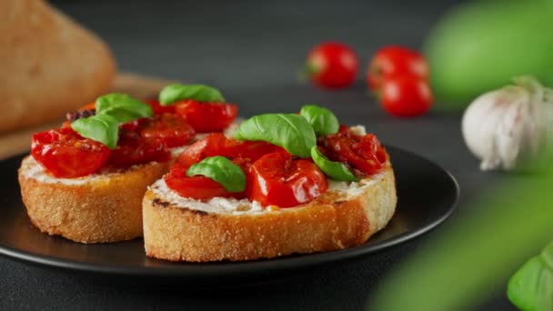 Bruschetta Serem Ricotto Pomidorami Wiśniowymi Bazylią Czosnkiem Czarnym Tle Jedzenie — Wideo stockowe