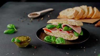 Jambonlu Ciabatta Sandviçi, Pesto sosu, Domates, siyah arka planda Basil. Yiyecekler. Yemek arkaplanı. Yakın plan.