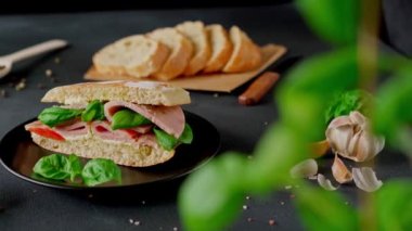 Jambonlu Ciabatta Sandviçi, Pesto sosu, Domates, siyah arka planda Basil. Yiyecekler. Yemek arkaplanı. Yakın plan.