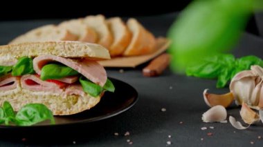 Jambonlu Ciabatta Sandviçi, Pesto sosu, Domates, siyah arka planda Basil. Yiyecekler. Yemek arkaplanı. Yakın plan.