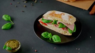 Jambonlu Ciabatta Sandviçi, Pesto sosu, Domates, siyah arka planda Basil. Yiyecekler. Gıda arkaplanı