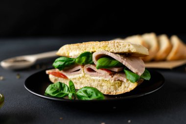 Jambonlu Ciabatta Sandviçi, Pesto sosu, Domates, siyah arka planda Basil. Yiyecekler. Yemek arkaplanı. Yakın plan.