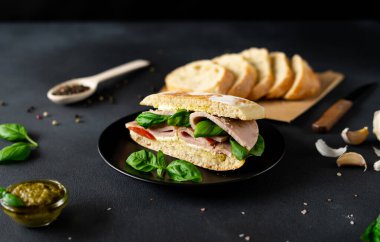 Jambonlu Ciabatta Sandviçi, Pesto sosu, Domates, siyah arka planda Basil. Yiyecekler. Gıda arkaplanı