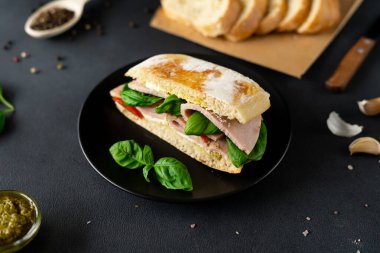 Jambonlu Ciabatta Sandviçi, Pesto sosu, Domates, siyah arka planda Basil. Yiyecekler. Yemek arkaplanı. Yakın plan.