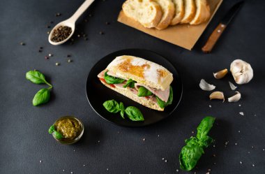 Jambonlu Ciabatta Sandviçi, Pesto sosu, Domates, siyah arka planda Basil. Yiyecekler. Gıda arkaplanı