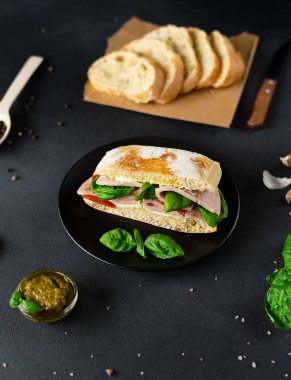 Jambonlu Ciabatta Sandviçi, Pesto sosu, Domates, siyah arka planda Basil. Yiyecekler. Gıda arkaplanı