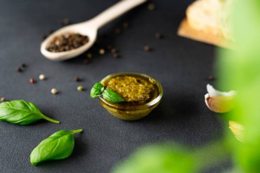 Cam kasede pesto sosu, fesleğen, siyah arka planda karabiber. Gıda arkaplanı