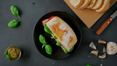 Jambonlu Ciabatta Sandviçi, Pesto sosu, Domates, siyah arka planda Basil. Yiyecekler. Yemek arkaplanı. Üst görünüm