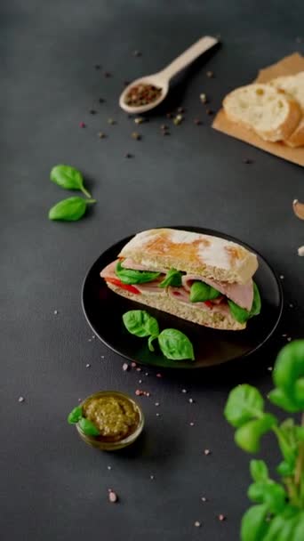 加火腿 意式酱汁 罗勒等配以黑色底色的查巴塔三明治 食品背景 垂直录像 — 图库视频影像
