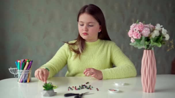 Uzun Saçlı Sarı Kazaklı Küçük Bir Kız Boncuklu Mücevherler Örüyor — Stok video