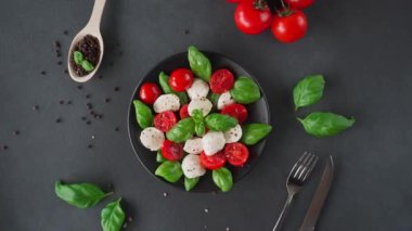Olgun domatesli Caprese salatası ve siyah arka planda taze fesleğen yapraklı mozzarella peyniri. İtalyan yemeği.