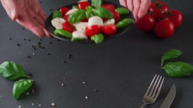 Olgun domatesli Caprese salatası ve siyah arka planda taze fesleğen yapraklı mozzarella peyniri. İtalyan yemeği.