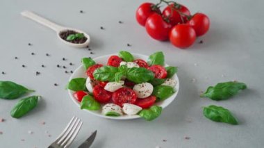 Olgun domatesli Caprese salatası ve açık arkaplanda taze fesleğen yapraklı mozzarella peyniri. İtalyan yemeği.