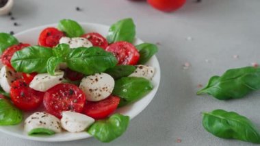 Olgun domatesli Caprese salatası ve açık arkaplanda taze fesleğen yapraklı mozzarella peyniri. İtalyan yemeği. Yakın plan.