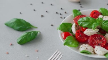 Dilimlenmiş domatesli İtalyan Caprese salatası, mozzarella peyniri, fesleğen, hafif arka planda zeytinyağı. Yakın plan.