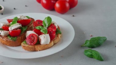 Peynirli tost, domates ve açık arkaplanda fesleğen. İtalyan yemeği.