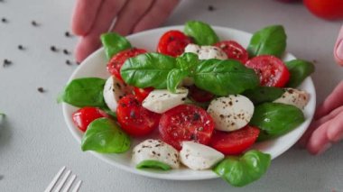 Olgun domatesli Caprese salatası ve açık arkaplanda taze fesleğen yapraklı mozzarella peyniri. İtalyan yemeği. Yakın plan.