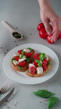 Taze domates, mozzarella ve açık arkaplanlı Basil yapraklı Caprese Hughchetta. Vejetaryen yemeği. Dikey video