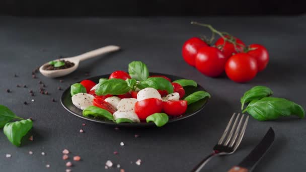 辣椒色拉配成熟的西红柿和带有新鲜罗勒叶的莫扎拉奶酪 背景为黑色 意大利食品 — 图库视频影像