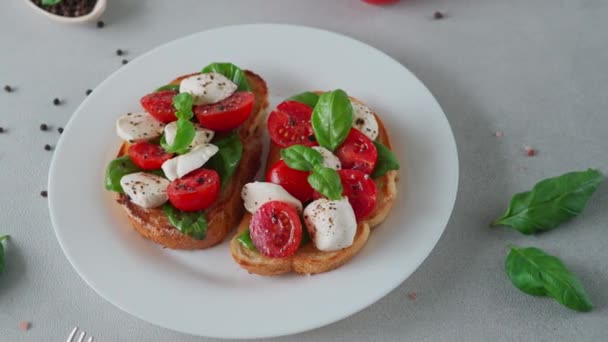 Zbliżenie Bruschetty Pomidorami Mozzarellą Liśćmi Bazylii Jasnym Tle Crostino Caprese — Wideo stockowe