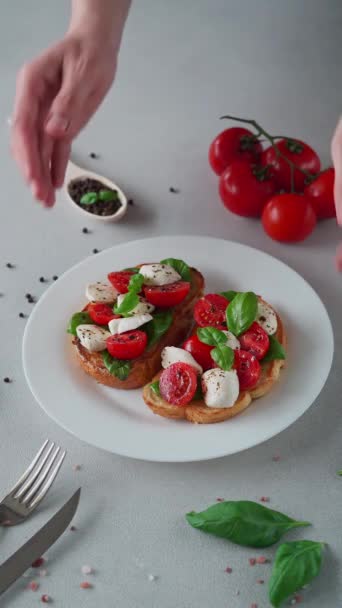 Bruschetta Mit Tomaten Mozzarella Und Basilikumblättern Auf Hellem Hintergrund Vertikales — Stockvideo
