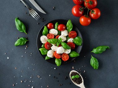 Olgun domatesli Caprese salatası ve siyah arka planda taze fesleğen yapraklı mozzarella peyniri. İtalyan yemeği. Üst görünüm