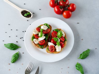 Taze domates, mozzarella ve açık arkaplanlı Basil yapraklı Caprese Hughchetta. Vejetaryen yemeği.