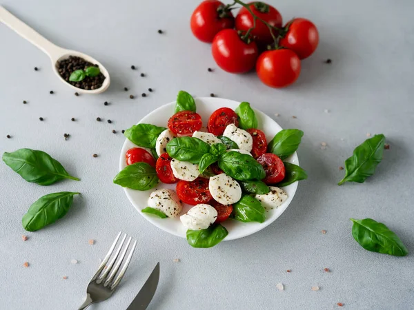 stock image Italian Caprese salad with sliced tomatoes, mozzarella cheese, basil, olive oil on light background. Vegetarian food