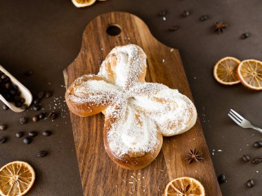 Tahta üzerinde hindistan cevizi cipsi ve vanilya kremalı tatlı spiral çörek. Kahverengi arka planda fırın hamur işleri. Yakın plan.