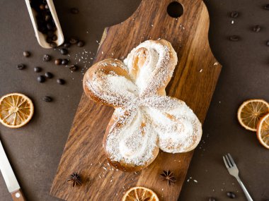 Tahta üzerinde hindistan cevizi cipsi ve vanilya kremalı tatlı spiral çörek. Kahverengi arka planda fırın hamur işleri. Yakın plan.