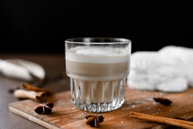 Cappuccino ve tahtada krema olan beyaz kekler. Kahverengi arka planda Latte Macchiato. Yakın plan.