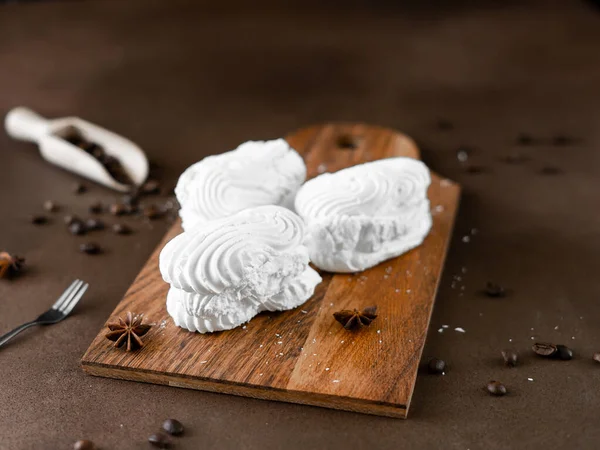 White Meringue cookies with cream on wooden board. Whipped egg cream cookies on brown background
