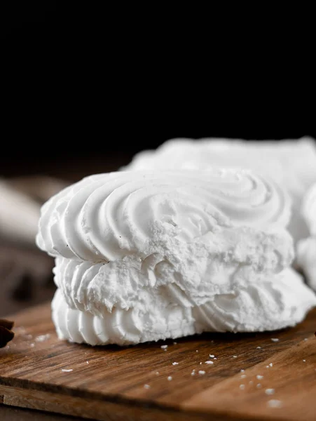 White Meringue cookies with cream on wooden board. Whipped egg cream cookies on brown background. Close-up