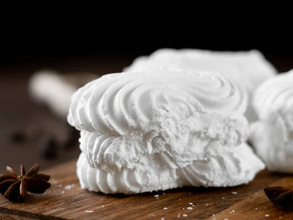 White Meringue cookies with cream on wooden board. Whipped egg cream cookies on brown background. Close-up