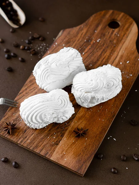 White Meringue cookies with cream on wooden board. Whipped egg cream cookies on brown background. Top view