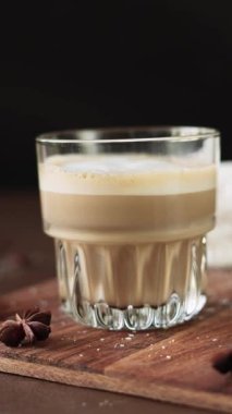 Cappuccino ve tahtada krema olan beyaz kekler. Kahverengi arka planda Latte Macchiato. Yakın plan.