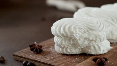 Tahtada krema olan beyaz kremalı kurabiyeler. Kahverengi arka planda çırpılmış yumurta kremalı kurabiyeler. Yakın plan.