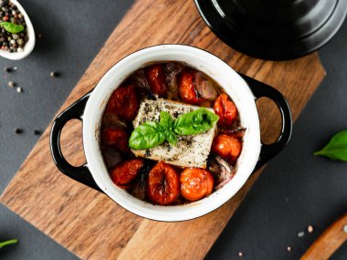 Feta peyniri, mavi soğan, kiraz domatesleri ve siyah arka planda baharatlarla zeytin yağında pişirilmiş fesleğen. Üst görünüm