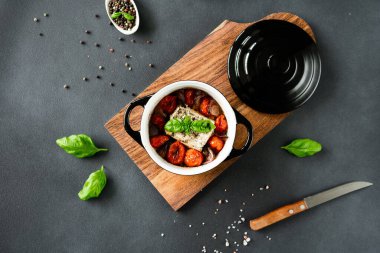 Feta peyniri, mavi soğan, kiraz domatesleri ve siyah arka planda baharatlarla zeytin yağında pişirilmiş fesleğen. Üst görünüm