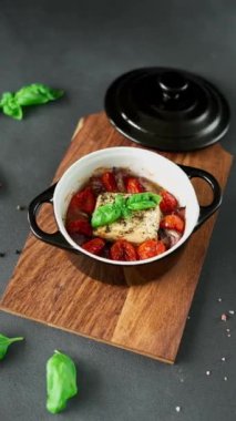 Feta peyniri, mavi soğan, kiraz domatesleri ve siyah arka planda baharatlarla zeytin yağında pişirilmiş fesleğen.