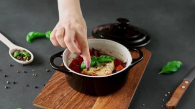 Feta peyniri, mavi soğan, kiraz domatesleri ve siyah arka planda baharatlarla zeytin yağında pişirilmiş fesleğen.