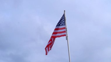 Amerikan Bayrağı. ABD ulusal bayrağı mavi gökyüzüne karşı rüzgarda dalgalanıyor. Yavaş çekim