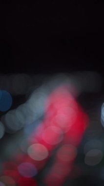 Bir gece şehrindeki trafik sıkışıklığının bulanık arkaplanı. Şehirdeki trafik sıkışıklığı çözüldü. Dikey video