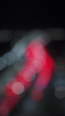 Bir gece şehrindeki trafik sıkışıklığının bulanık arkaplanı. Şehirdeki trafik sıkışıklığı çözüldü. Dikey video