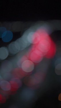 Bir gece şehrindeki trafik sıkışıklığının bulanık arkaplanı. Şehirdeki trafik sıkışıklığı çözüldü. Dikey video