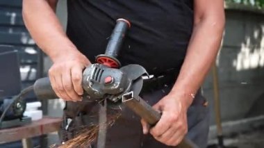 Metal tüpü Angle Grinder kullanarak kesen bir işçi. Parlak kıvılcımlar ve parıltılar