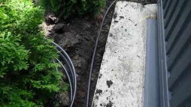Güç hattı kablosuyla kazılmış siper. İşçiler bir inşaat sahasında yere elektrik kabloları döşüyorlar.
