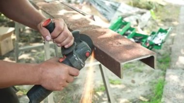 Metal tüpü Angle Grinder kullanarak kesen bir işçi. Parlak kıvılcımlar ve parıltılar